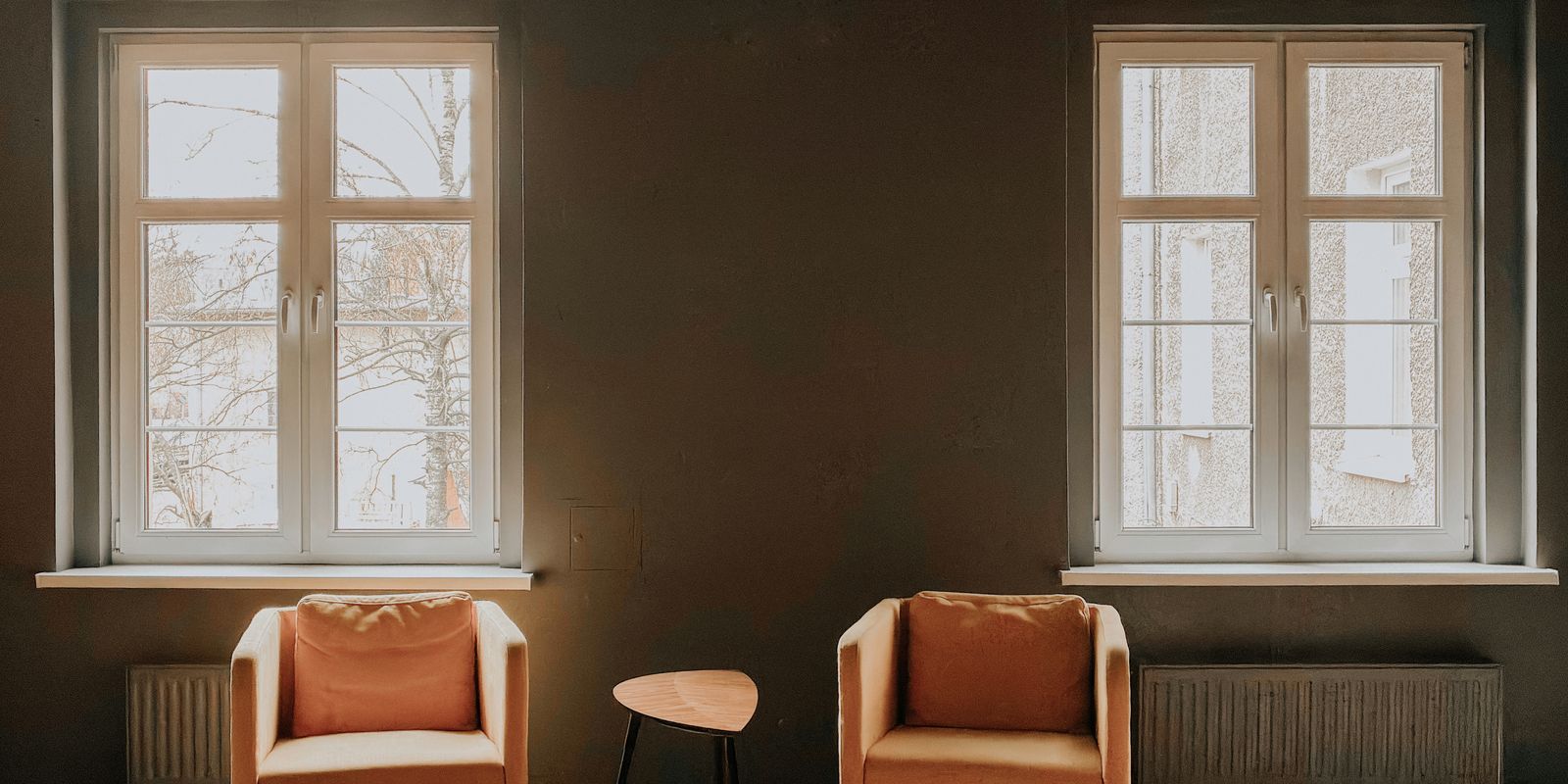 Sitting room with two tall windows and armchairs