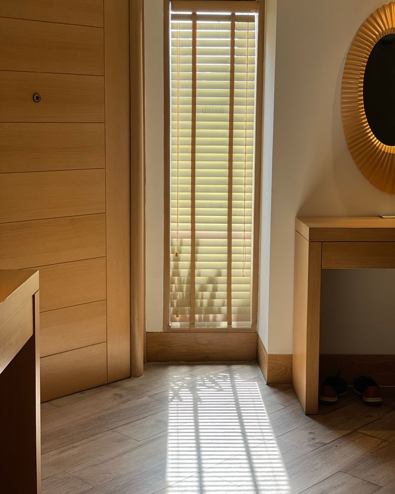 Warm light through wood blinds in a tall window